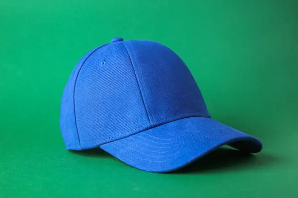 Stylish blue baseball cap on green background