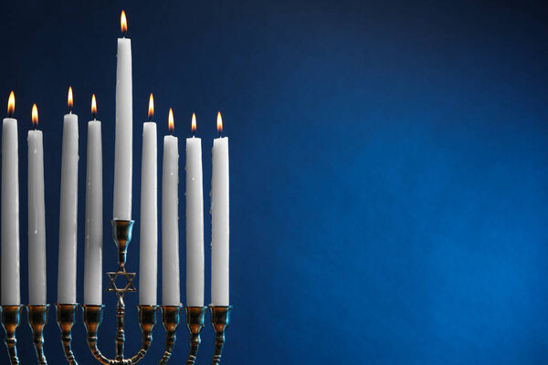 Hanukkah celebration. Menorah with burning candles on blue background, space for text