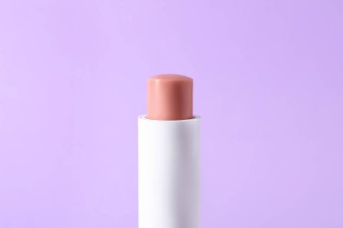 Leylak arkaplanda bir dudak kremi, yakın plan. Kozmetik ürünü