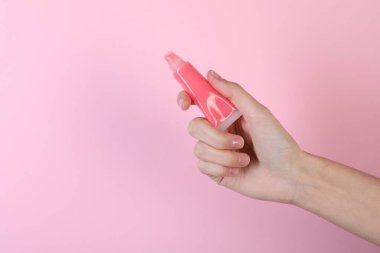 Pembe arka planda dudak merhemi olan kadın, yakın plan.