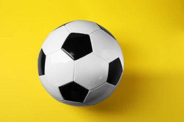 Sarı arka planda bir futbol topu, manzaranın üstünde. Spor malzemeleri.