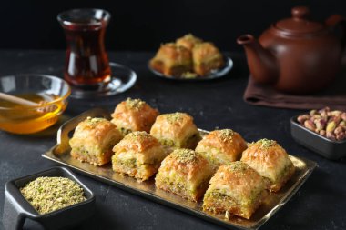 Koyu dokulu masada servis edilen doğranmış fındıklı enfes taze baklava. Doğu tatlıları