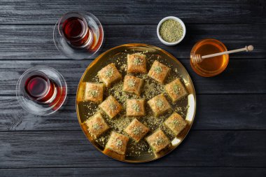 Siyah ahşap masada servis edilen, doğranmış fındıklı enfes taze baklava. Doğu tatlıları