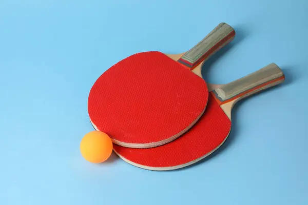 stock image Ping pong ball and rackets on light blue background