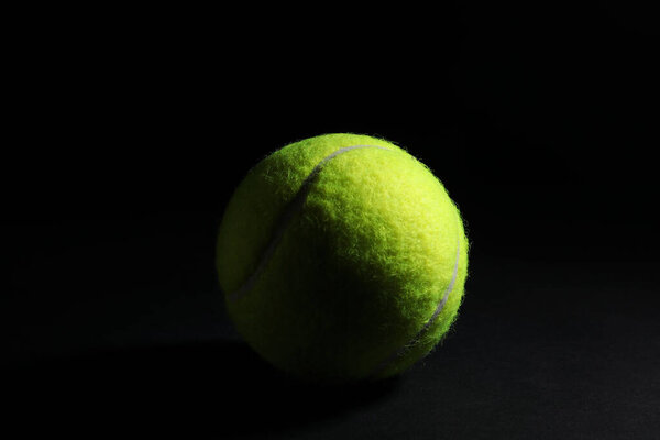 One bright tennis ball on black background