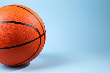 Açık mavi arka planda turuncu bir basketbol topu, yakın plan. Metin için boşluk