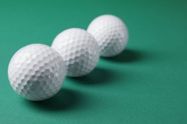 Yeşil arka planda üç golf topu, yakın plan. Metin için boşluk