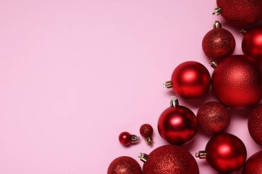 Pembe arka planda parlak kırmızı Noel topları, düz yatış. Metin için boşluk