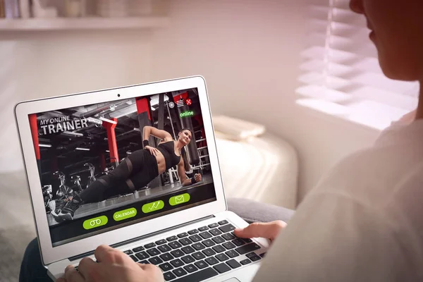 Personal trainer online. Man viewing website via laptop at home, closeup