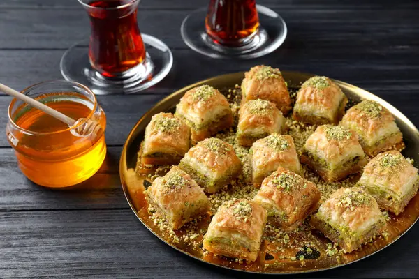 Delicious fresh baklava with chopped nuts served on black wooden table. Eastern sweets