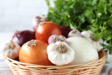 Hasır sepette taze çiğ sarımsak ve soğan, yakın plan.