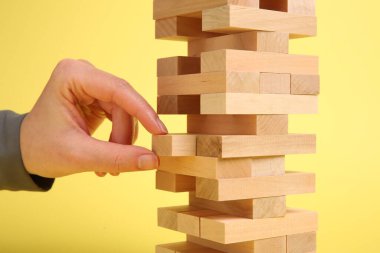 Sarı arka planda Jenga kulesi oynayan kadın, yakın plan.