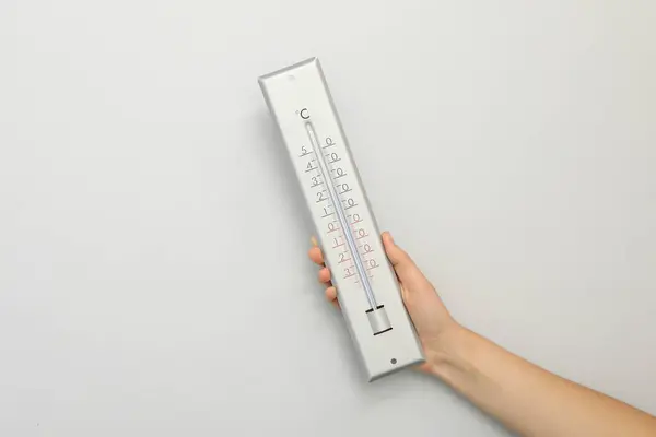 Woman with weather thermometer on white background, closeup. Space for text