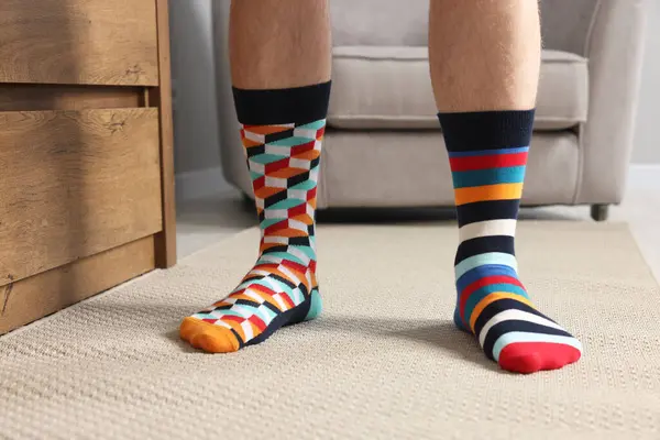 Man in different stylish socks indoors, closeup