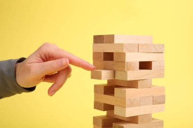 Sarı arka planda Jenga kulesi oynayan kadın, yakın plan.
