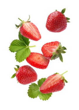 Taze olgun çilekler ve yeşil yapraklar beyaz arka plana dökülüyor.