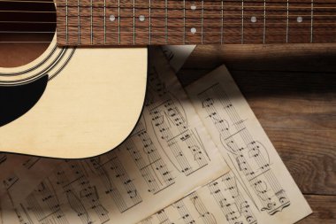 Kağıt kağıtlar, notalar ve akustik gitarla ahşap masa, üst manzara.