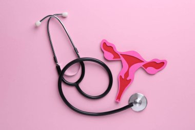 Reproductive medicine. Paper uterus and stethoscope on pink background, top view clipart