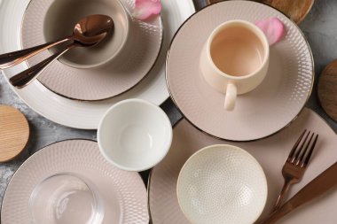 Masa dekorları çok şık. Tabaklar, çatal bıçak takımı, fincan ve yapraklar gri yüzeyde, düz yatıyordu.