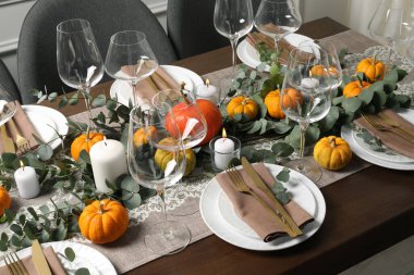 Güzel bir sonbahar sofrası. Tabaklar, çatal bıçak, gözlük, balkabağı ve çiçek dekoru.