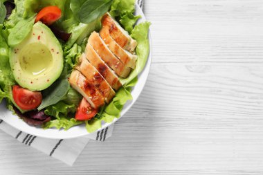 Tavuk, vişneli domates ve beyaz ahşap masadaki avokado ile nefis bir salata. Metin için boşluk