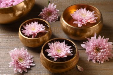 Tibet şarkı kaseleri, su ve ahşap masada güzel çiçekler.