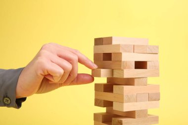 Sarı arka planda Jenga kulesi oynayan kadın, yakın plan.