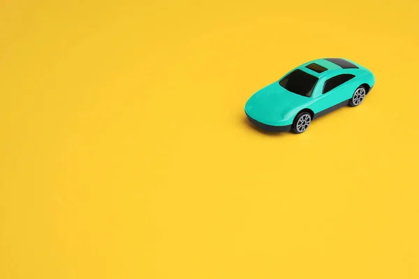 One turquoise car on yellow background, space for text. Children`s toy