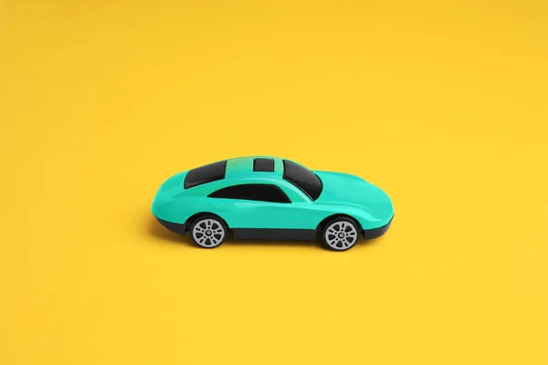 One turquoise car on yellow background. Children`s toy