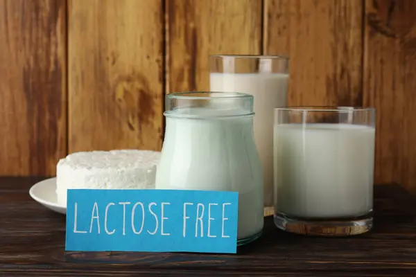 Card with phrase Lactose free and different fresh products on wooden table