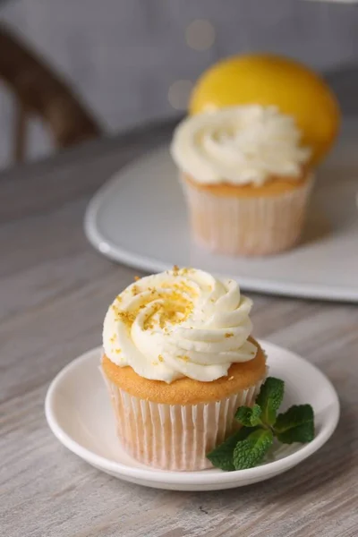 Delicious lemon cupcake with white cream and mint on table, closeup