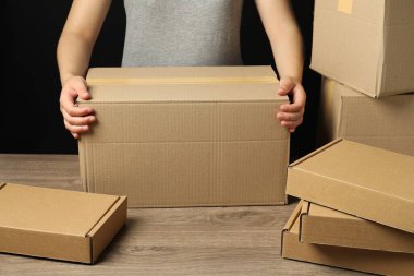 Paketleme malları. Ahşap masada karton kutuları olan kadın, yakın plan.