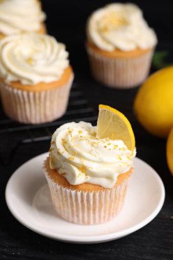 Siyah masada beyaz kremalı leziz limonlu kekler, yakın plan.
