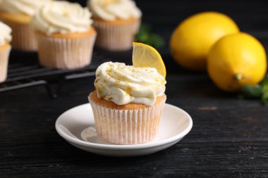 Beyaz kremalı, limonlu ve siyah ahşap masada limonlu lezzetli kekler, yakın plan.