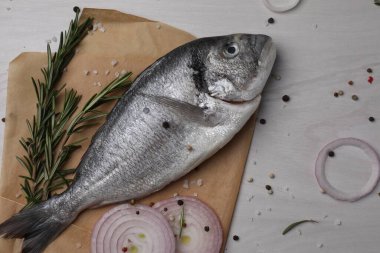 Çiğ dorado balığı, baharatlar ve soğan beyaz ahşap masa, düz uzanmış