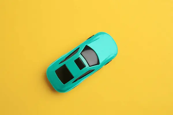 One turquoise car on yellow background, top view. Children`s toy