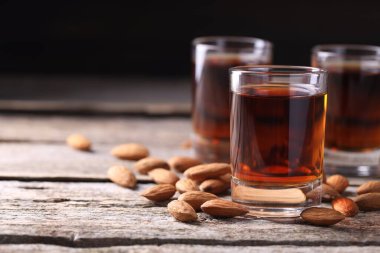 Lezzetli amaretto likörlü bardaklar ve ahşap masada badem, yakın plan. Metin için boşluk
