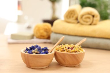 Kuru çiçekli kaseler ve açık ahşap masada kaşıklar. Spa terapisi