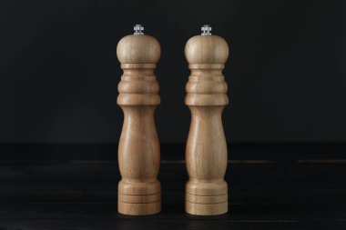 Siyah ahşap masada tuzluk ve biberlikler, yakın plan.