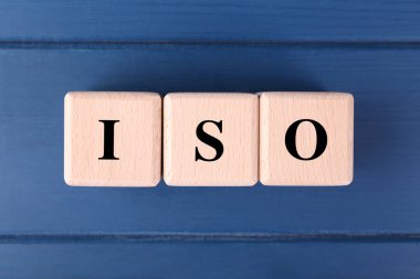 Uluslararası Standartlaştırma Örgütü. Mavi ahşap masada kısaltılmış ISO küpleri, üst görünüm