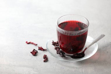 Bardakta Aromatik amber çayı, kurutulmuş roselle kalibreleri ve ışık masasında kaşık, mesaj için yer.