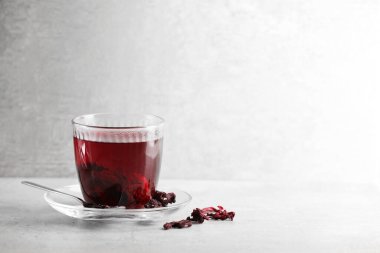 Bardakta Aromatik amber çayı, kurutulmuş roselle kalibreleri ve ışık masasında kaşık, mesaj için yer.