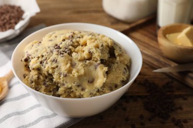 Çikolatalı kurabiye hamuru kasede ve malzemeler beyaz ahşap masada, yakın plan.