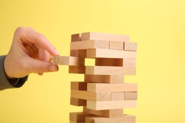 Sarı arka planda Jenga kulesi oynayan kadın, yakın plan.