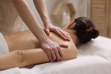 Spa salonundaki kanepede sırt masajı yaptıran kadın.