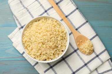 Lezzetli bulgur kasede ve kaşık açık mavi ahşap masada, üst manzara