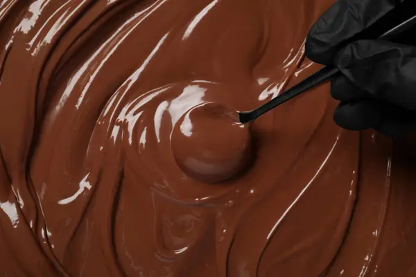 Person making tasty milk chocolate paste, top view