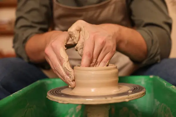 Clay crafting. Man making bowl on potter\'s wheel indoors, closeup
