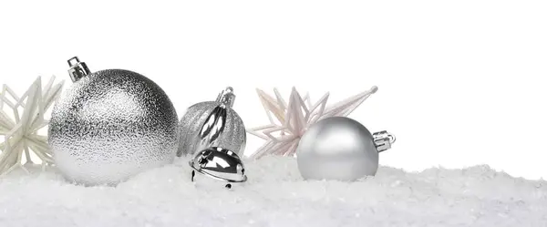 Beautiful silver Christmas balls and decorative snowflakes on snow against white background