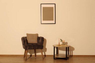 Rahat koltuk, yastık, masa ve dekorasyon elemanları bej duvarlı odada. İç tasarım